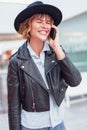 Young stylish urban woman joking into phone indoors