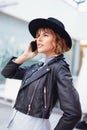 Young stylish urban woman looking away and calling indoors