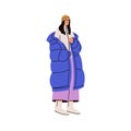 Young stylish woman in fashion winter outfit. Modern girl wearing warm puffer coat and hat. Female standing in cold