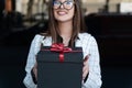 Young stylish woman hands gift. Happy young woman holds gift box and smiling. Black gift box with red bow