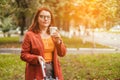 Beautiful young woman having fun drinking morning coffee in sunlight while walking through colorful autumn forest Royalty Free Stock Photo