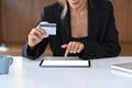 Stylish woman holding debit card and making payment online or shopping online on digital tablet. Royalty Free Stock Photo