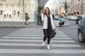 Young stylish woman holds shopping bag and walk on the street. Girl after shopping with paper bags crosses the road Royalty Free Stock Photo