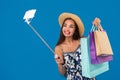 Young stylish woman posing and taking a selfie on the phone with shopping bags on a blue background Royalty Free Stock Photo