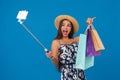 Young stylish woman posing and taking a selfie on the phone with shopping bags on a blue background Royalty Free Stock Photo