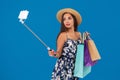 Young stylish woman posing and taking a selfie on the phone with shopping bags on a blue background Royalty Free Stock Photo