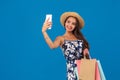 Young stylish woman posing and taking a selfie on the phone with shopping bags on a blue background Royalty Free Stock Photo