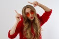 Young stylish woman with red lips, sunglasses and sweatshirt poiting copy space  on white background. Closeup girl face Royalty Free Stock Photo