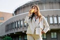 Young stylish woman in the street drinking morning coffee in sunshine light Royalty Free Stock Photo