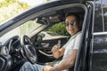 A young successful Asian businessman in sunglasses is sitting in an expensive modern car and smiling, looking at the camera Royalty Free Stock Photo