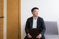 Young successful Asian man, waiting for a job interview, in the waiting room of the office center, sitting on a chair near the Royalty Free Stock Photo