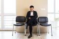 Young Asian man, waiting for a job interview, in the waiting room of the office center, sitting on a chair near the Royalty Free Stock Photo