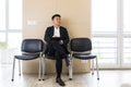 Young  Asian man, waiting for a job interview, in the waiting room of the office center, sitting on a chair near the Royalty Free Stock Photo