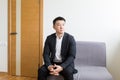 Young successful Asian man, waiting for a job interview, in the waiting room of the office center, sitting on a chair near the Royalty Free Stock Photo