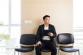 Young successful Asian man, waiting for a job interview, in the waiting room of the office center, sitting on a chair near the Royalty Free Stock Photo
