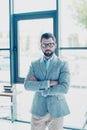 Young successful bearded nerdy man is standing in his office in