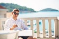 Young successful business man enjoying espresso coffee beverage in sunny marine panoramic cafe. Royalty Free Stock Photo