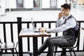 Young successful business man sitting in outdoor urban cafe with laptop and talking on phone Royalty Free Stock Photo