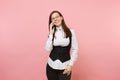 Young successful business woman in black suit and glasses holding and talking on mobile phone on pastel pink Royalty Free Stock Photo