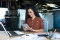 Young successful business woman working inside modern office building, Hispanic woman using tablet computer smiling and Royalty Free Stock Photo