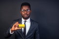 Young successful businessman credit broker in a stylish black classic suit and in cool glasses holding a yellow plastic