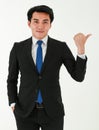 Young successful businessman in a formal black suit is looking and pointing his finger away while standing on white background Royalty Free Stock Photo