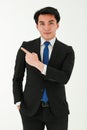 Young successful businessman in formal black suit is looking to camera and pointing his finger away while standing on white Royalty Free Stock Photo