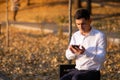 Young and successful businessman standing in park and reading a message on his smartphone Royalty Free Stock Photo