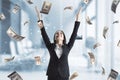 Young successful businesswoman with dollar bill money rain on blurry office interior background. Success, money and lottery winner Royalty Free Stock Photo