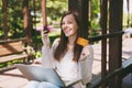 Young successful businesswoman holding credit card. Woman sitting on bench working on modern laptop pc computer in city Royalty Free Stock Photo