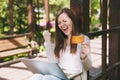 Young successful businesswoman holding credit card. Woman sitting on bench working on modern laptop pc computer in city Royalty Free Stock Photo