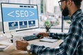 young successful developer sitting at workplace with SEO sign