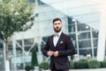 Young and successful. Handsome young man in full suit adjusting his jacket while standing outdoors Royalty Free Stock Photo