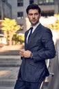 Young and successful. Handsome young man in full suit adjusting his jacket while standing outdoors Royalty Free Stock Photo