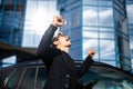 Young successful man, male executive businessman arms raised celebrating cheering shouting in front of a high rise office block in Royalty Free Stock Photo