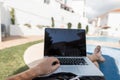 Young successful man manager with a modern laptop lies near the pool. Business freelancer works remotely on vacation.