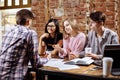 Young successful people are using a laptop, drinking coffee, talking and smiling while working in cafe. Royalty Free Stock Photo