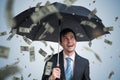 Young successful rich businessman with umbrella and money falling down. Royalty Free Stock Photo