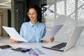 Young successful satisfied financier with paper work, hispanic woman reviewing reports and contracts, working with Royalty Free Stock Photo