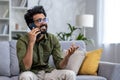 Young successful and smiling man talking on the phone while sitting on the sofa in the living room, Indian cheerfully Royalty Free Stock Photo