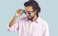 Young successful Indian man adjusts sunglasses and smiles self-confidently standing in studio
