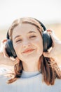 Young sunlit cute excited traveler tourist woman 20s wearing shirt summer casual clothes headphones listening to music