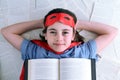 Young superhero girl reading a book