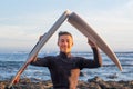 Young surfer comes out of the water carrying the broken board in the middle. Handsome guy with wetsuit. Horizon over the water