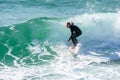 Young surfer enjoys the waves confronting the surf by surfing the rougher waters after a morning rain storm