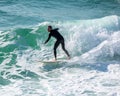 Young surfer enjoys the waves confronting the surf by surfing the rougher waters after a morning rain storm Royalty Free Stock Photo