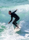 Young surfer enjoys the waves confronting the surf by surfing the rougher waters after a morning rain storm