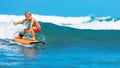 Young surfer learn to ride on surfboard on sea waves