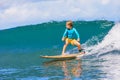 Young surfer learn to ride on surfboard on sea waves