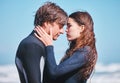 Young surfing couple hug, share intimate moment on beach vacation, flirting and playful. Girlfriend and boyfriend